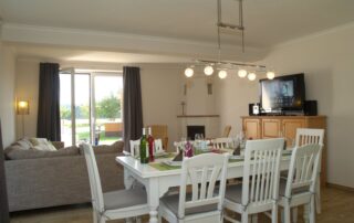 Essbereich mit Tisch für acht Personen, Kamin und Gartenblick im Ferienhaus Mira-Belle 1
