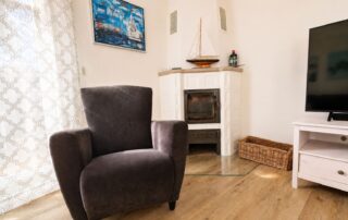 Gemütlicher Sessel vor dem Kamin im Wohnzimmer des Ferienhauses Mira-Belle 1 an der Ostsee