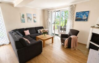 Wohnzimmer mit Ecksofa, Kamin und Zugang zur Terrasse im Ferienhaus Mira-Belle 1 in Kühlungsborn