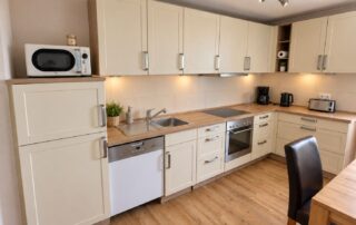 Voll ausgestattete Küche mit Geschirrspüler, Backofen, Kochfeld und Mikrowelle im Ferienhaus Mira-Belle 2