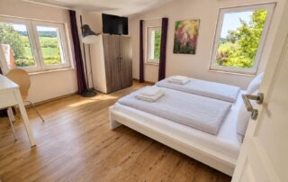 Helles Schlafzimmer mit Doppelbett und Blick ins Grüne im Ferienhaus Mira-Belle 2