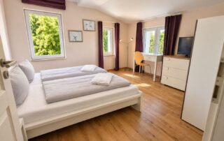 Schlafzimmer mit Doppelbett, Schreibtisch und TV im Ferienhaus Mira-Belle 2 an der Ostsee
